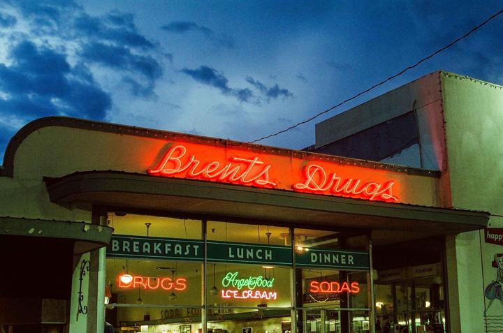 A building with neon signs for "Brents Drugs" and "Angel Food Ice Cream" is visible under a cloudy night sky.