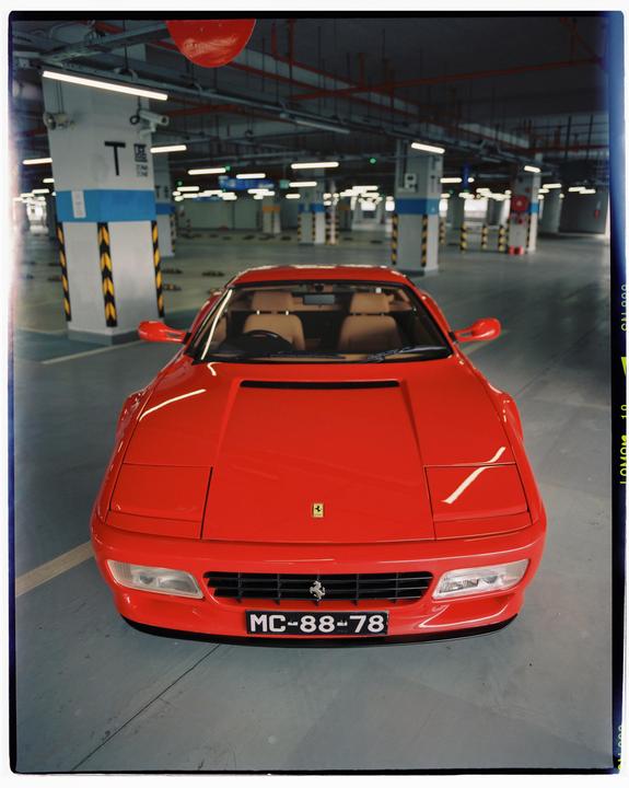 A red sports car is parked in an empty underground parking garage.
