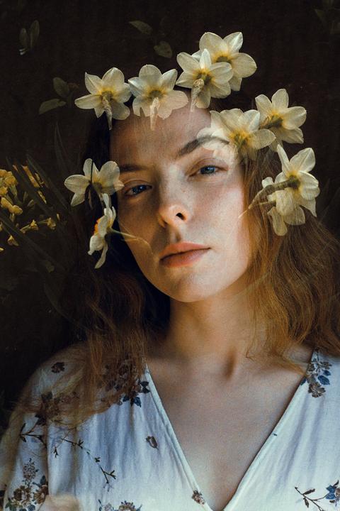 A woman with long hair and a floral dress is shown in a double exposure with narcissus flowers.
