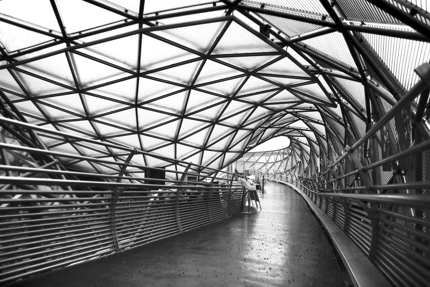 A long, curving walkway is covered by a geometric, triangular roof structure.