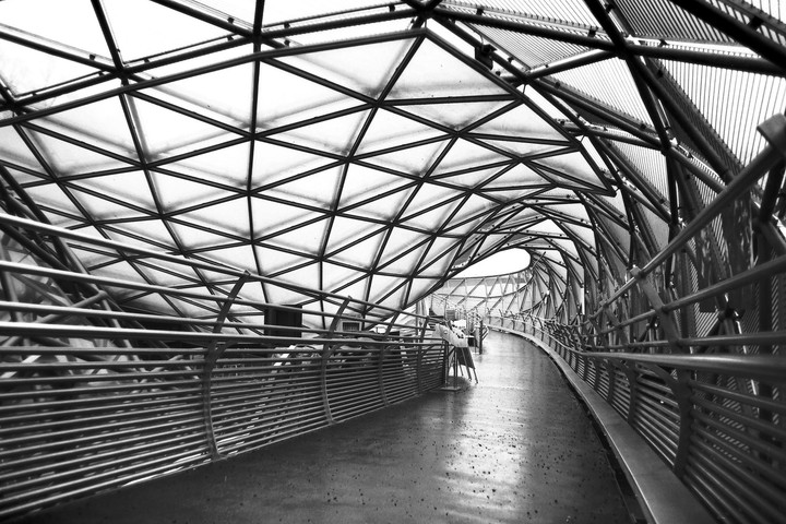 A long, curving walkway is covered by a geometric, triangular roof structure.