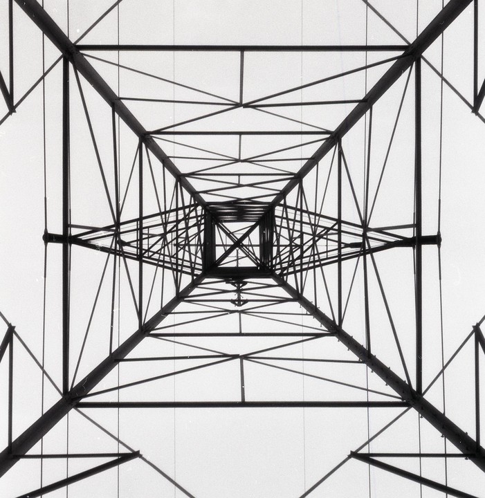 A low-angle view shows the converging lines of a metal structure against a bright sky.