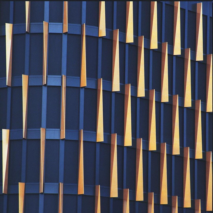 The facade of a building in Prague features a pattern of vertical gold panels against a dark blue background.