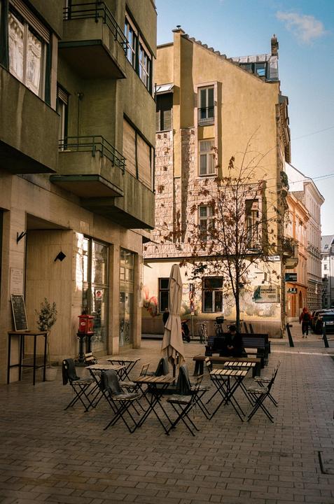 A cafe with outdoor seating is visible on a sunny morning in Budapest.