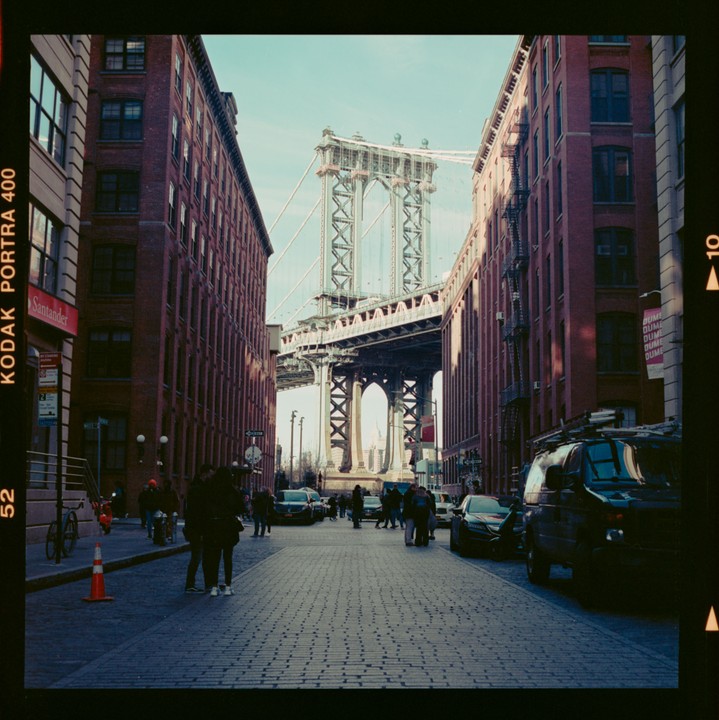 A street in New York is lined with brick buildings and leads to the Manhattan Bridge.