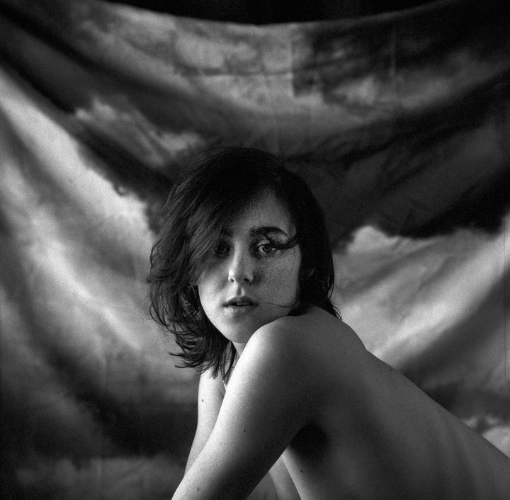 A woman with short hair looks over her shoulder at the viewer.