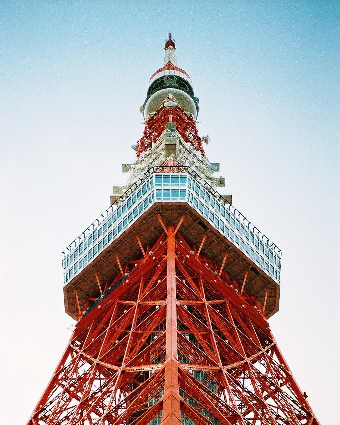 The Tokyo Tower is visible from a low angle, showing its red and white structure against a clear sky.