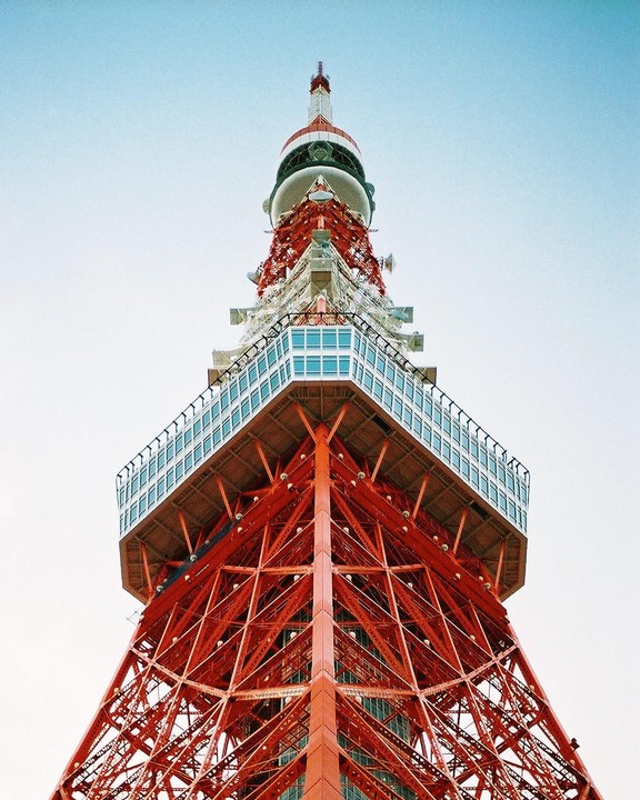 The Tokyo Tower is visible from a low angle, showing its red and white structure against a clear sky.