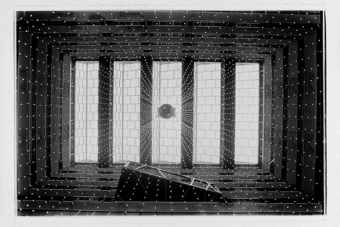 A low-angle view of the interior of a building shows a skylight and a geometric pattern of lights.