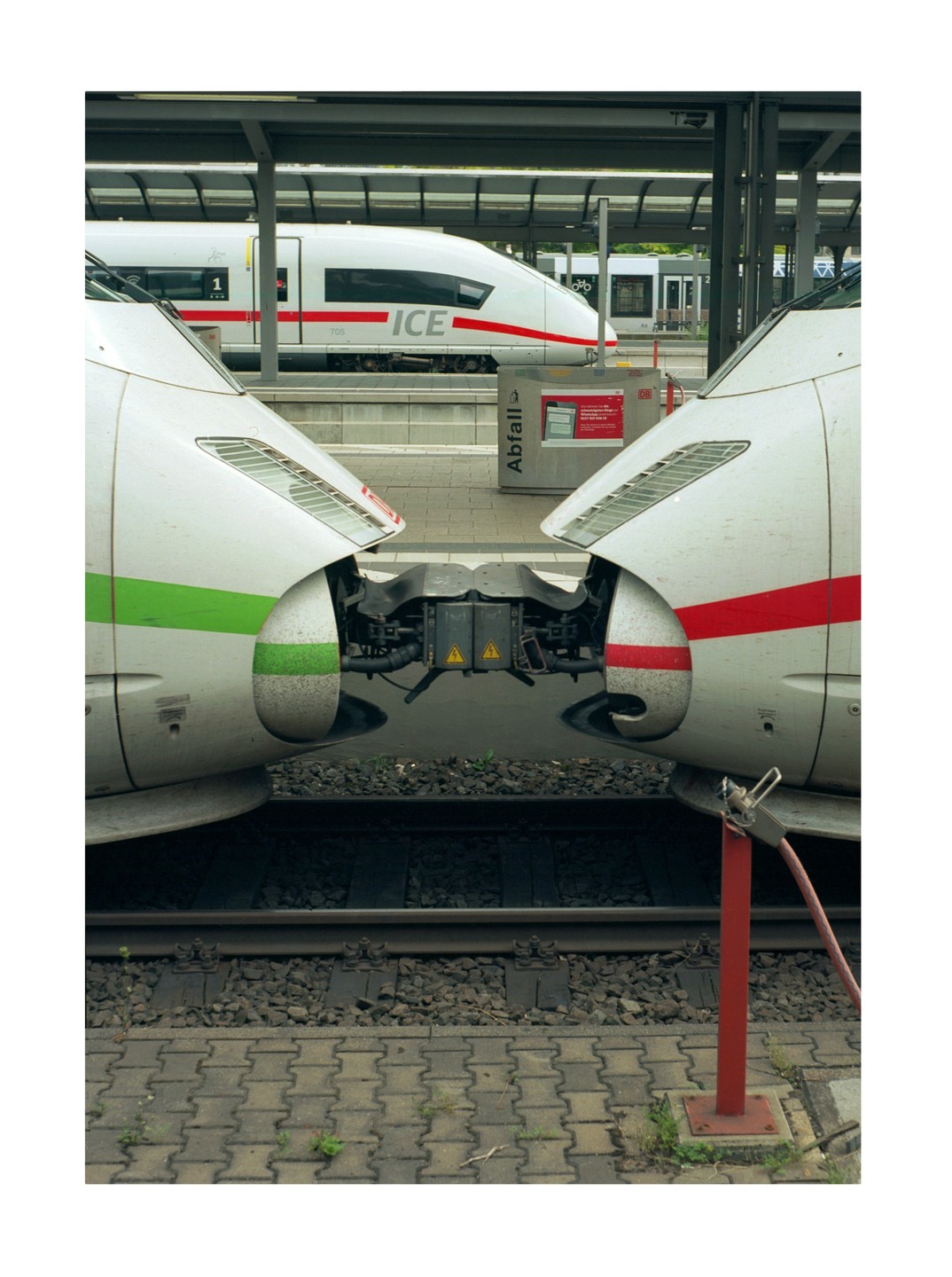 Two white trains are connected at a station platform, with another train visible in the background.