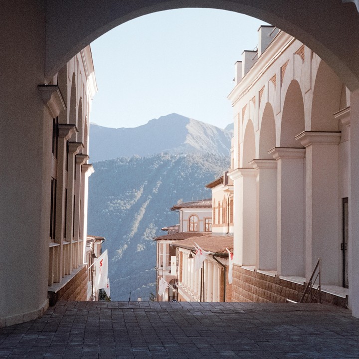 A mountain range is visible through an archway between two buildings.