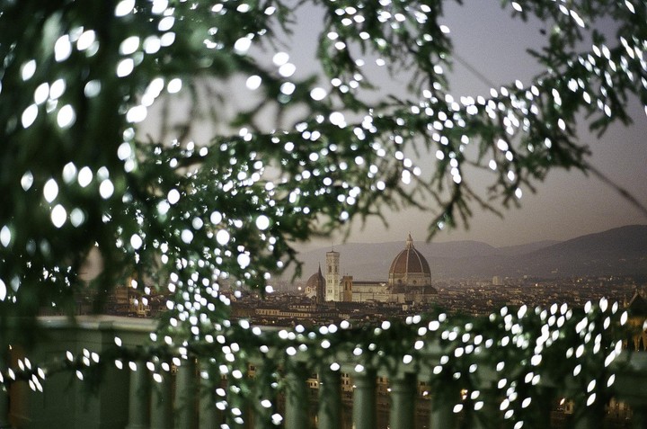 Christmas lights frame a view of the Florence Cathedral and city at night.