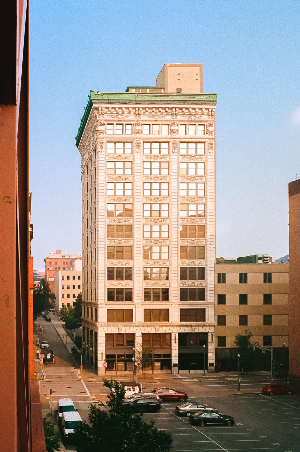 A tall, ornate building stands prominently in a city, with streets and other buildings visible below.
