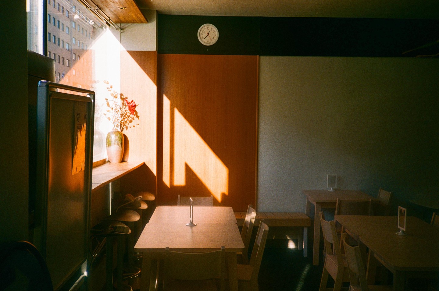 Sunlight streams through a window into a cafe with tables and chairs.