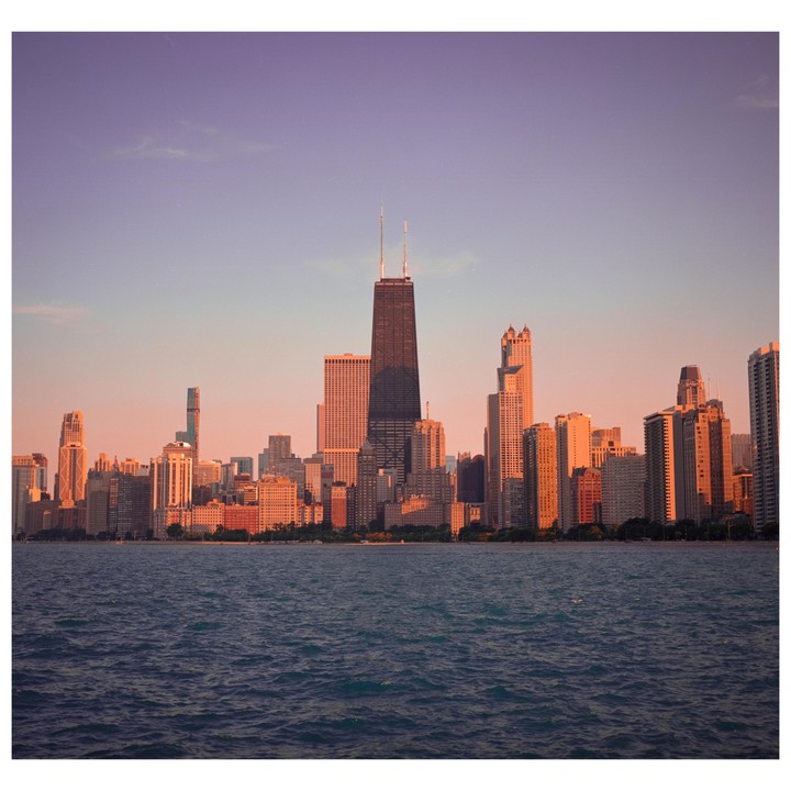 The Chicago skyline is visible across a body of water at sunset.