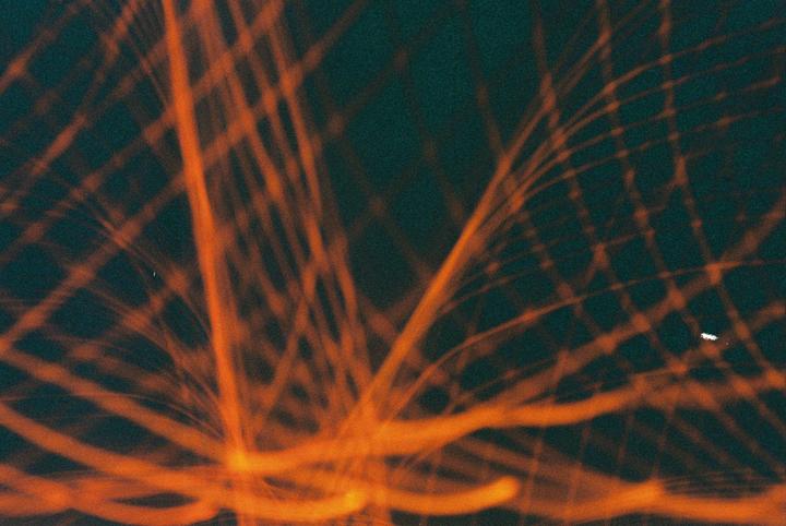 Orange light trails crisscross against a dark background.