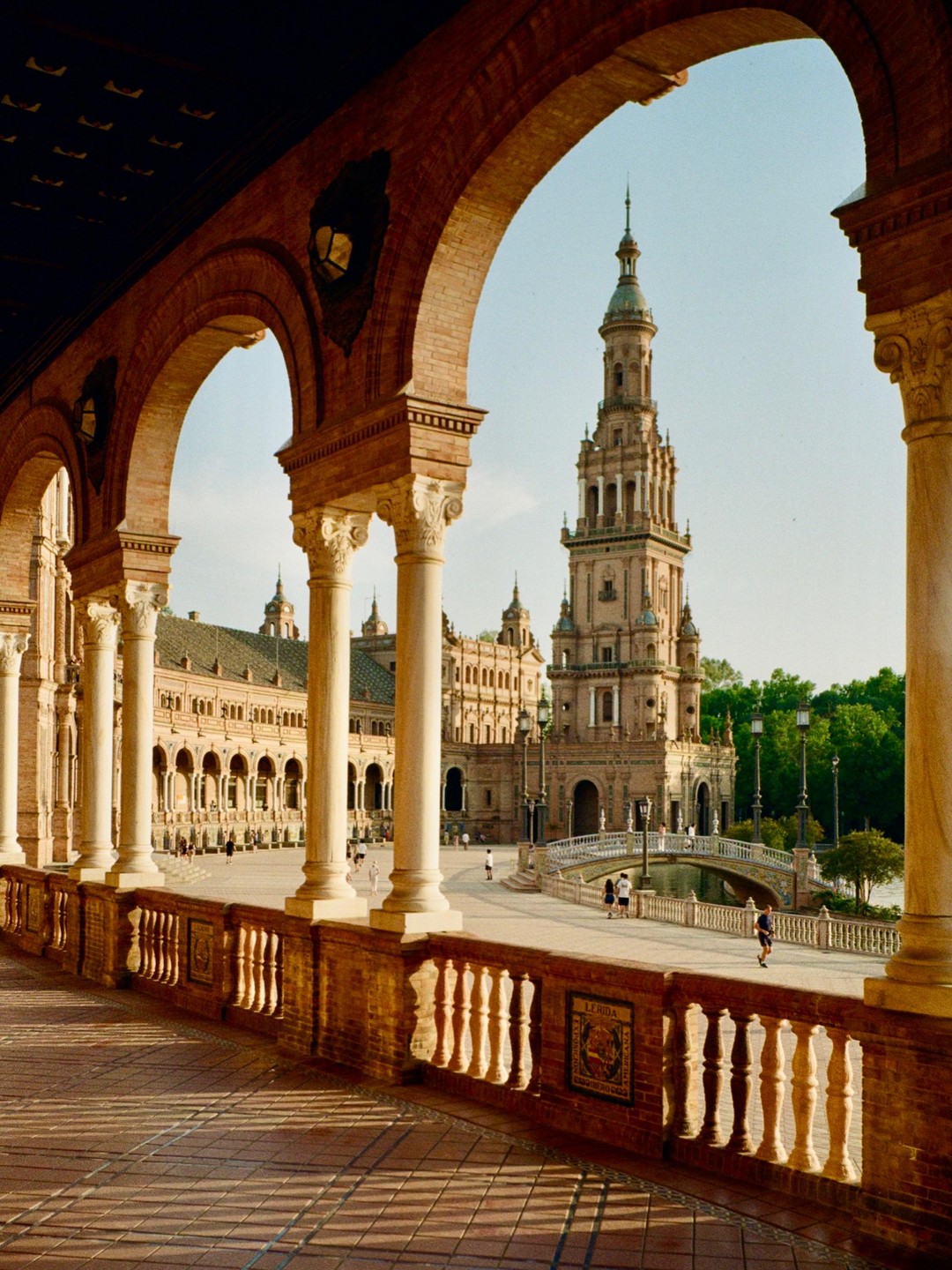 A large ornate building with a tall tower is visible through a series of arches and columns.