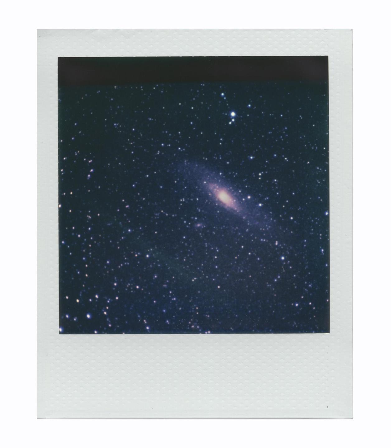The Andromeda Galaxy is visible in a dark sky filled with many stars.