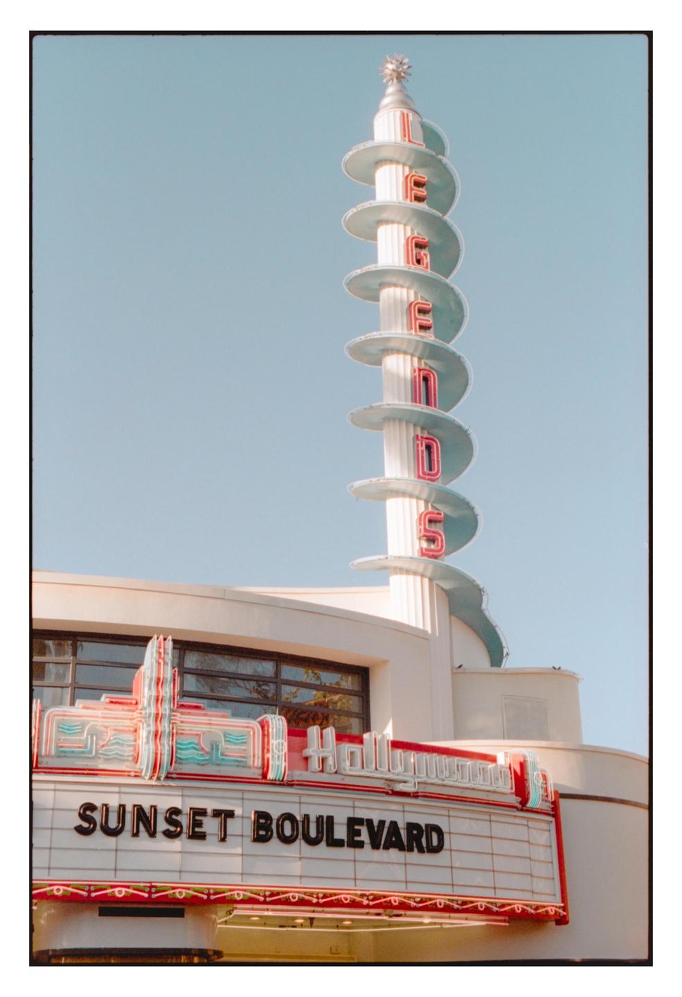 A tall, spiraling sign with neon letters spelling "LEGENDS" rises above a marquee that reads "SUNSET BOULEVARD."