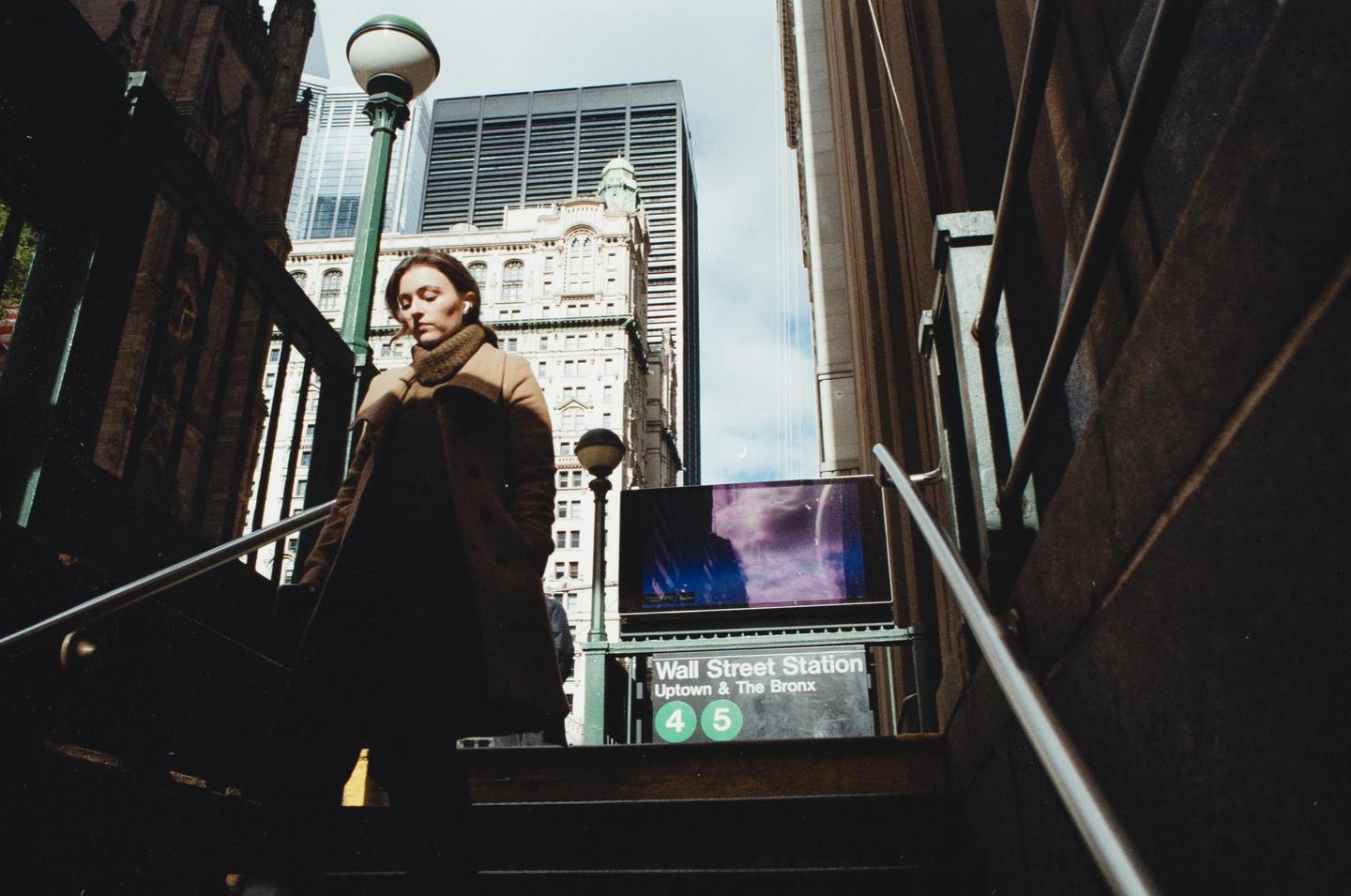 A woman descends the steps of the Wall Street subway station in New York.