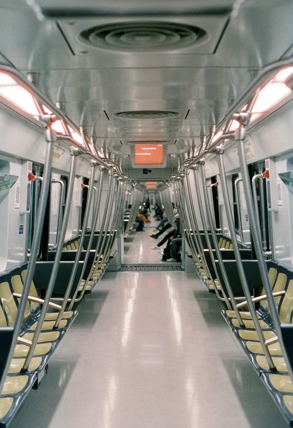 The interior of a subway car is visible, with rows of empty seats and a few passengers seated in the distance.