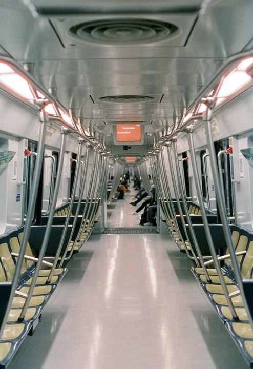 The interior of a subway car is visible, with rows of empty seats and a few passengers seated in the distance.