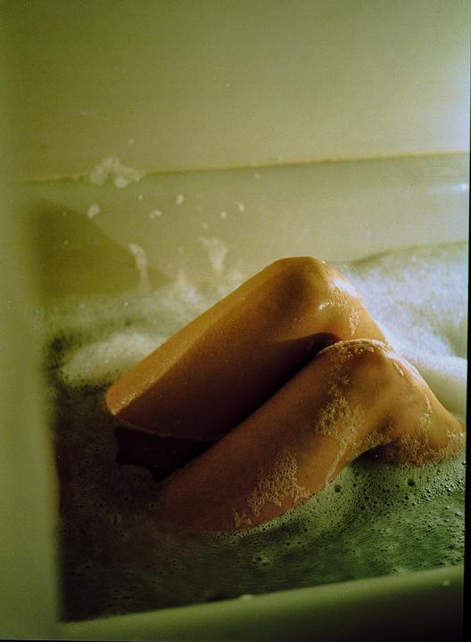 A person's legs are visible in a bubble bath.