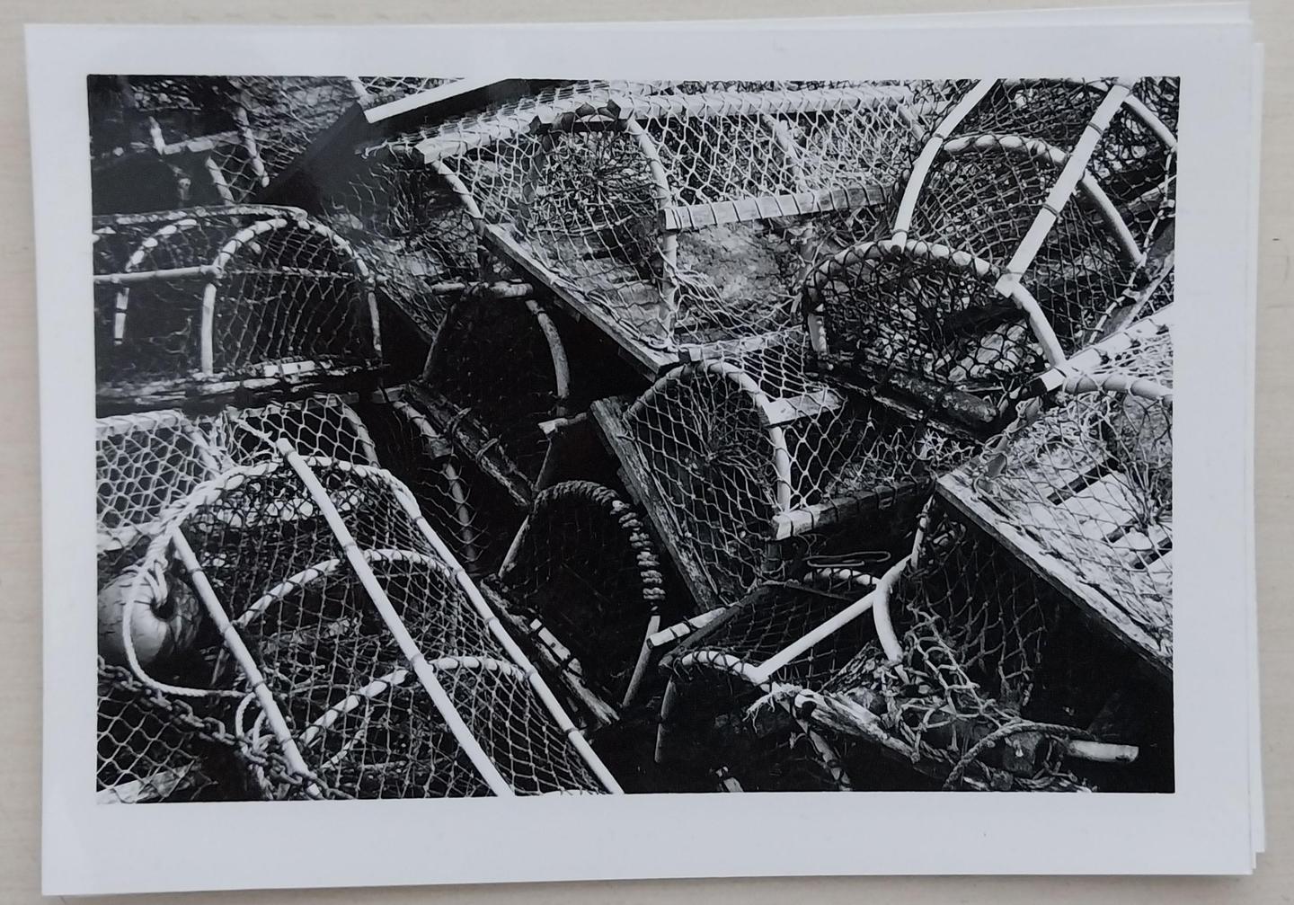 A pile of lobster pots with netting and floats is shown in black and white.
