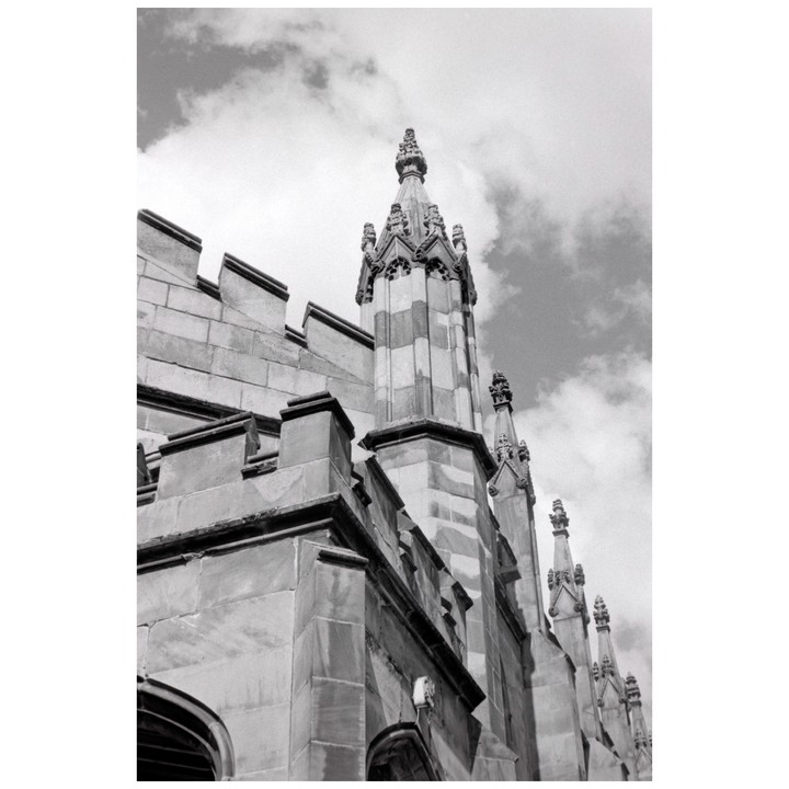 A low-angle view shows the stone facade of St Mary's church with decorative spires against a cloudy sky.