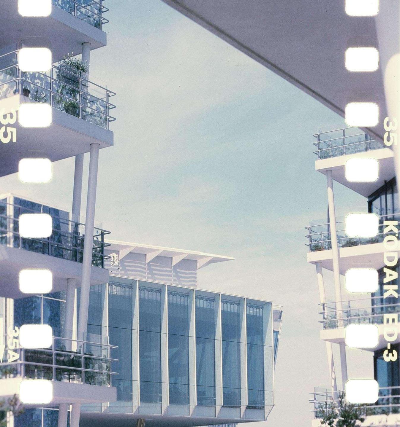 Modern buildings with balconies and large windows are visible against a clear sky.