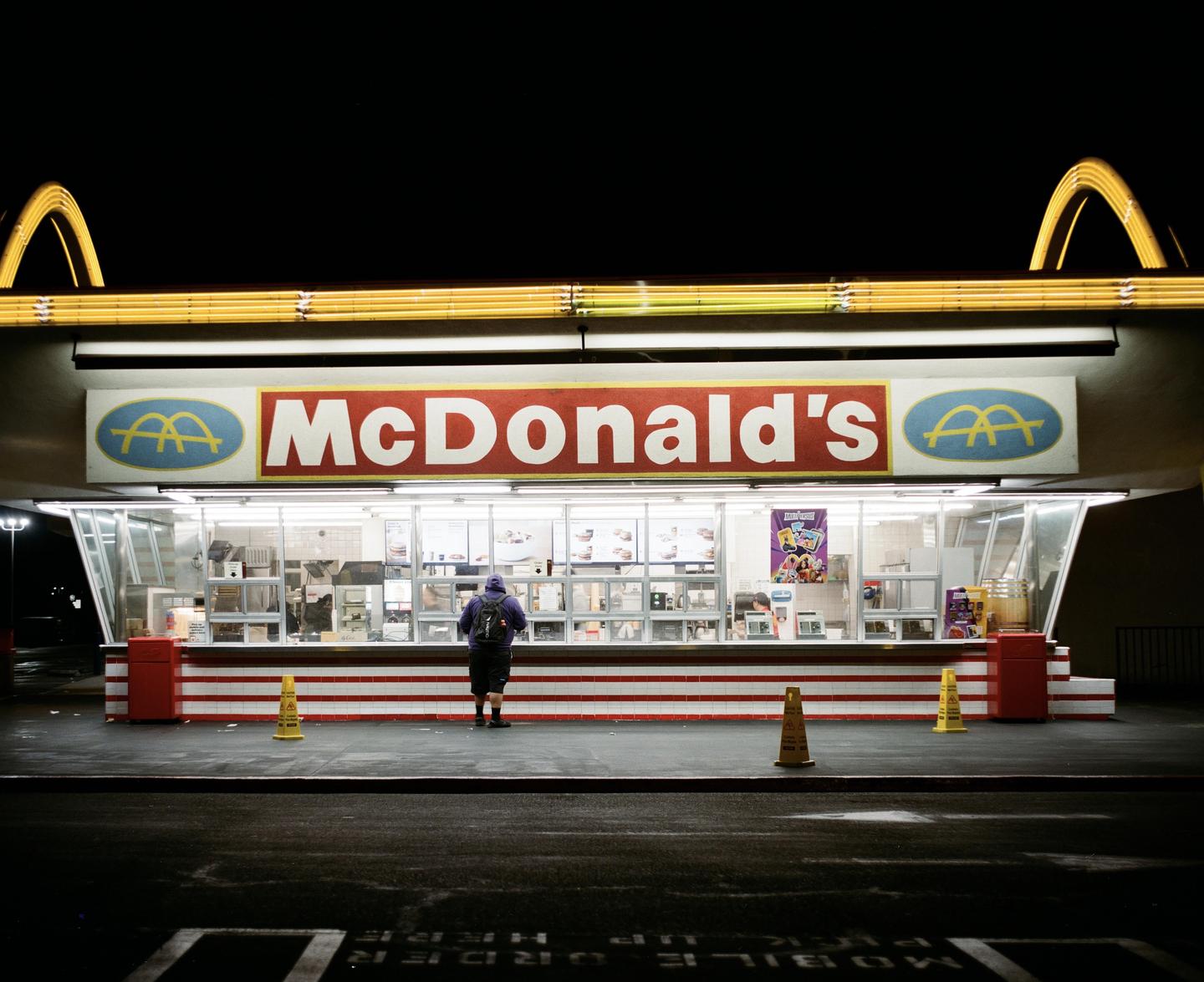 A person stands in front of a McDonald's restaurant at night.