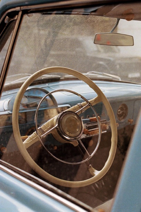 The interior of a vintage car is visible through the passenger side window, showing the steering wheel and dashboard.