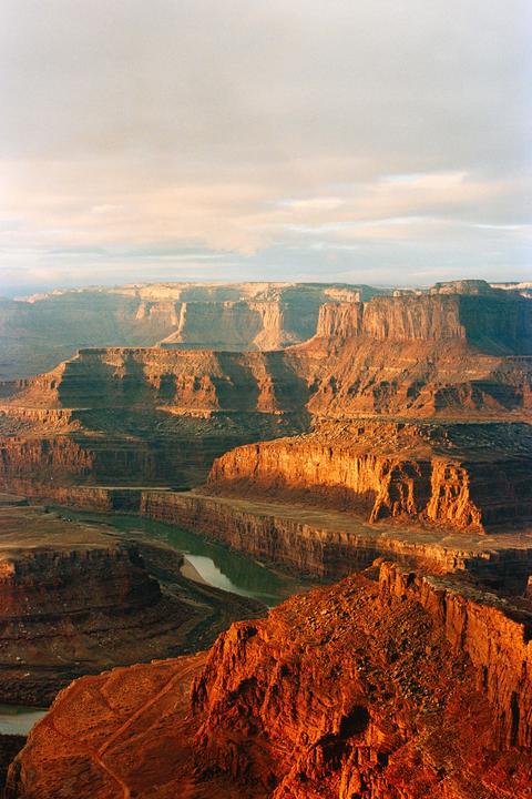 A river winds through a canyon with steep, rocky cliffs illuminated by the morning sun.