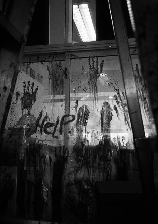 The word "Help" is written on a glass surface covered in handprints and streaks.