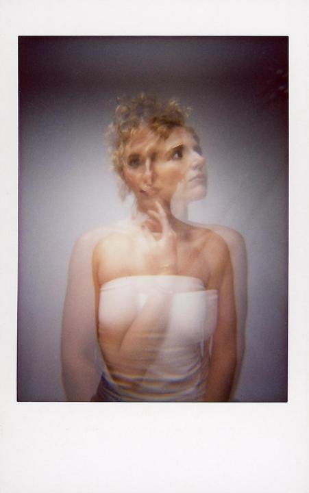 A woman with curly hair is captured in a double exposure, creating a blurred and layered effect.
