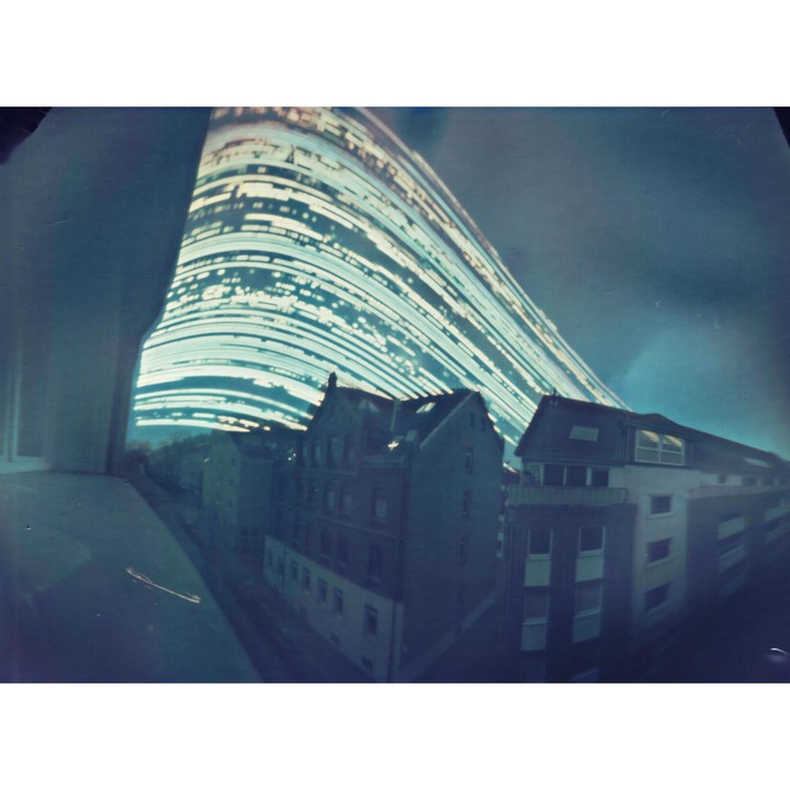 A long exposure photograph shows light trails arcing over buildings in Hannover, Germany.