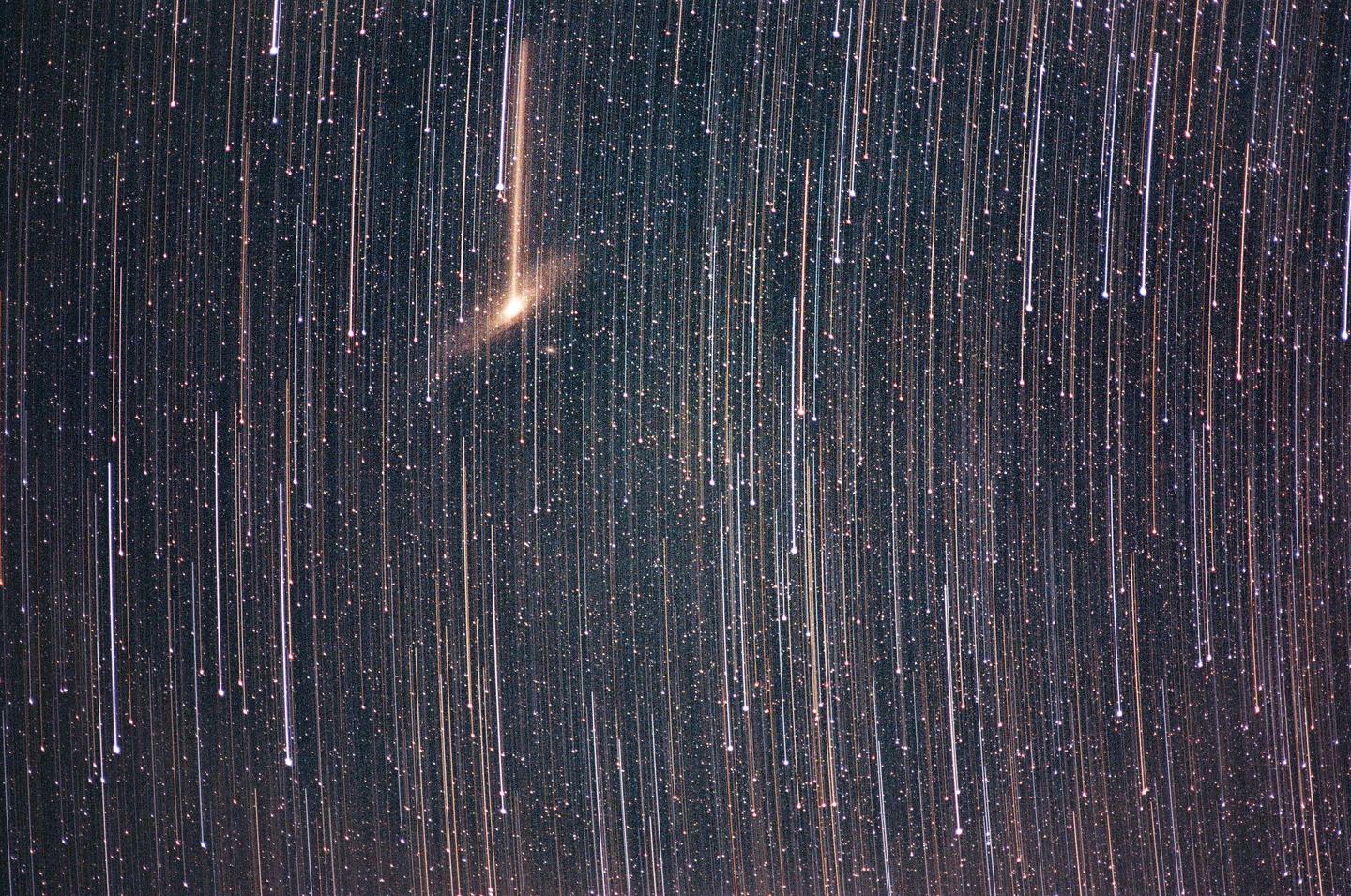 A long exposure photograph captures star trails and the Andromeda galaxy.
