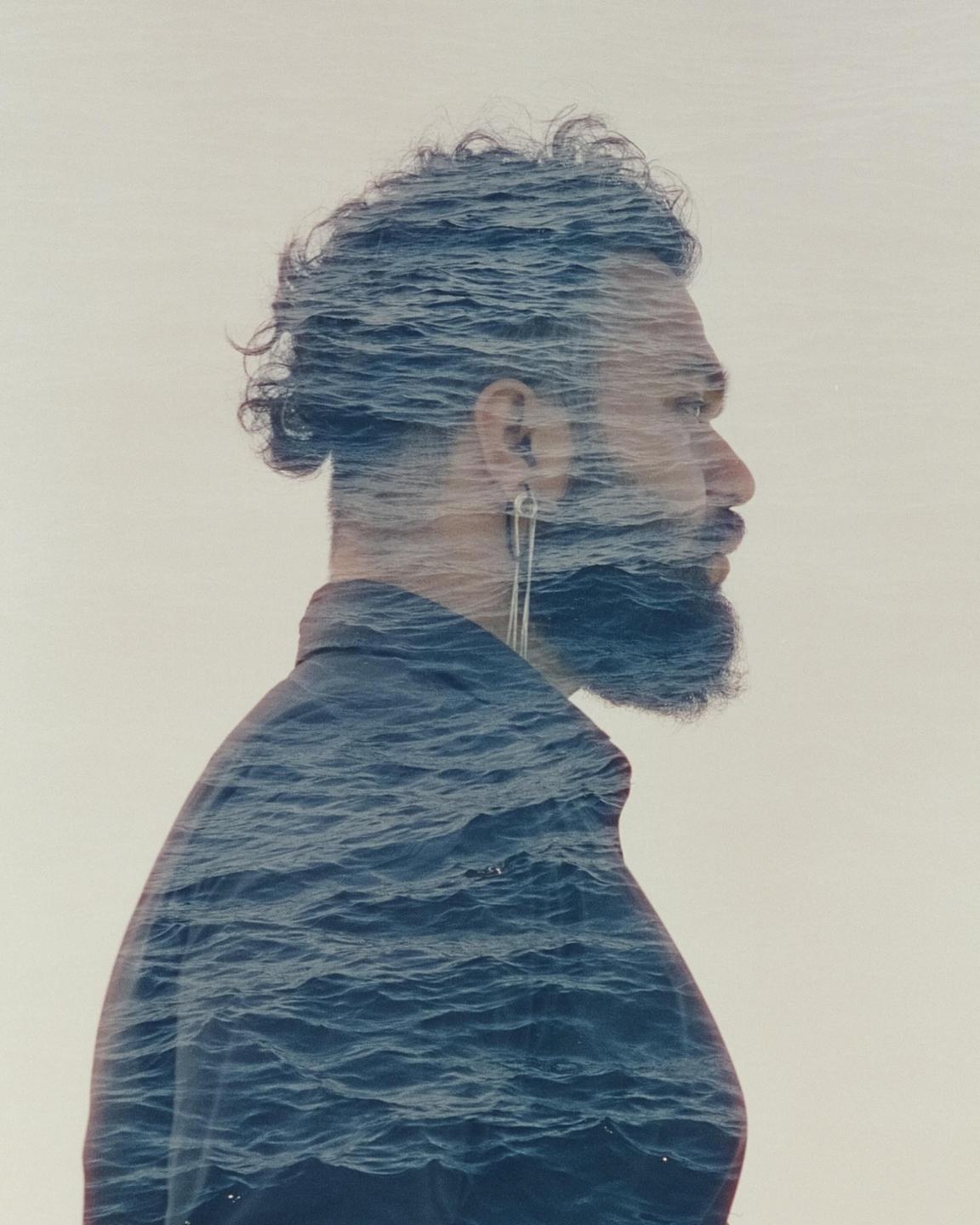 A man in profile is shown in a double exposure with ocean waves.