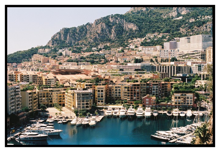 A harbor filled with boats is nestled at the base of a mountain covered in buildings.