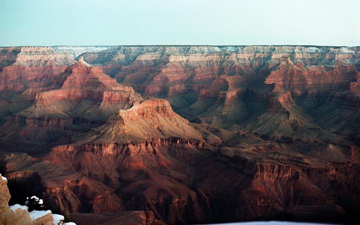 The Grand Canyon is visible with snow on the peaks and a clear sky.