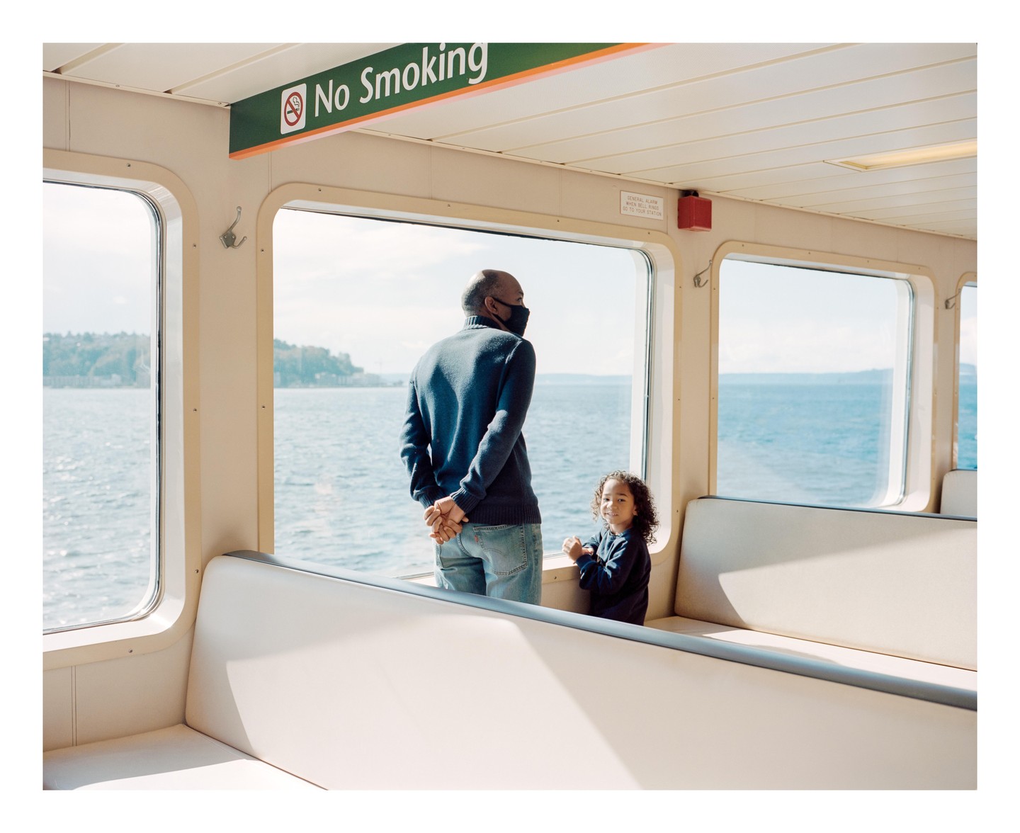 A man and a child are looking out the window of a boat with a "No Smoking" sign overhead.
