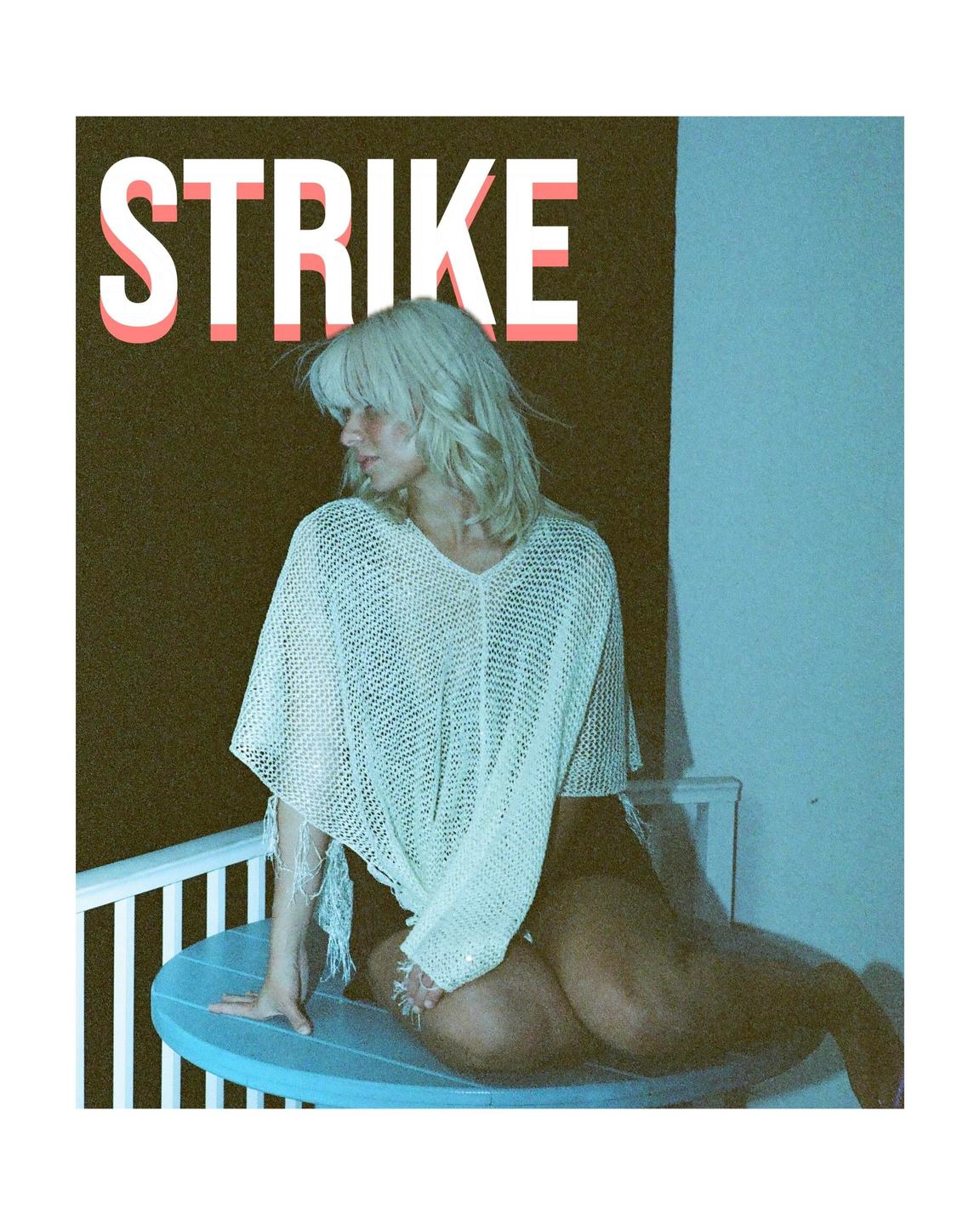 A woman with blonde hair poses on a blue surfboard with the word "STRIKE" in large letters above her.