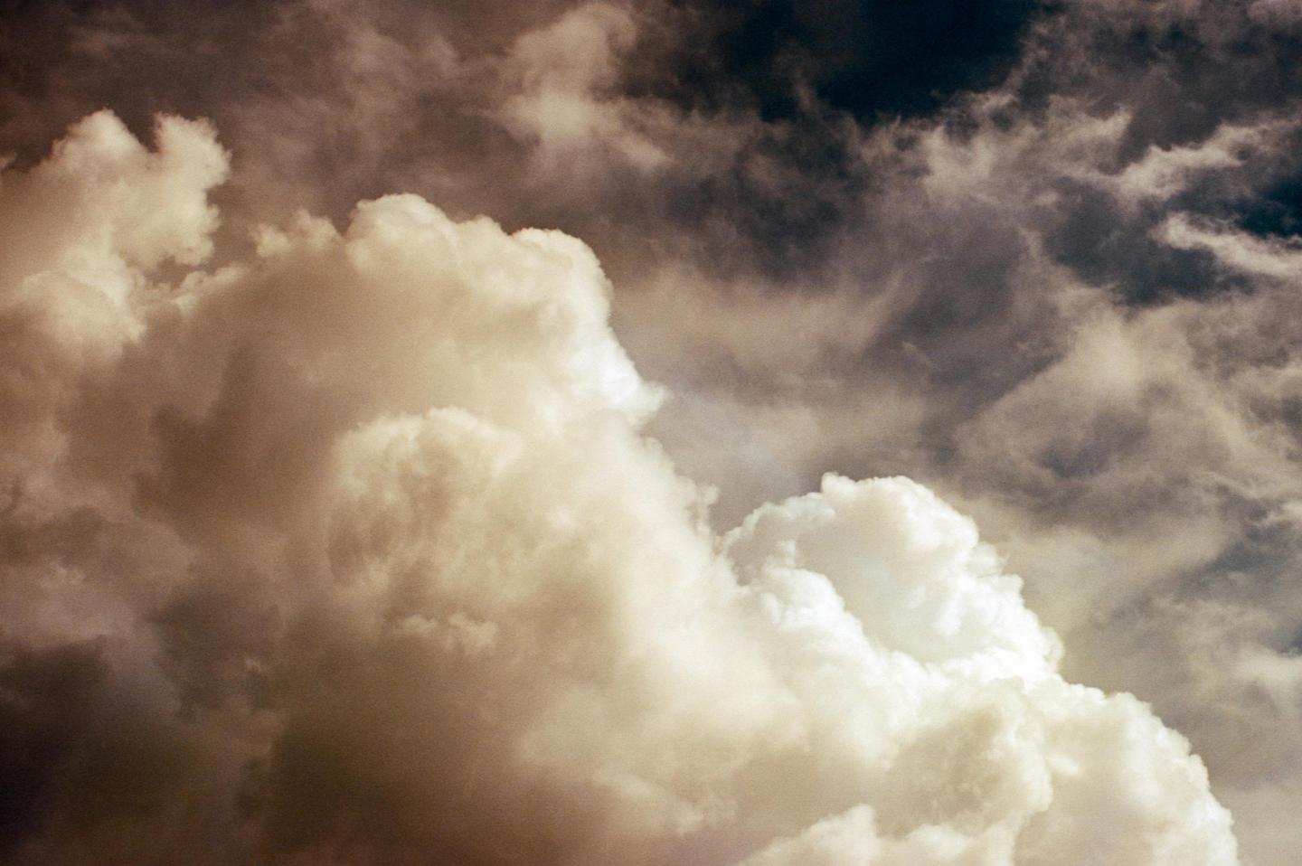 A dramatic sky is filled with large, fluffy clouds and darker, stormy clouds.