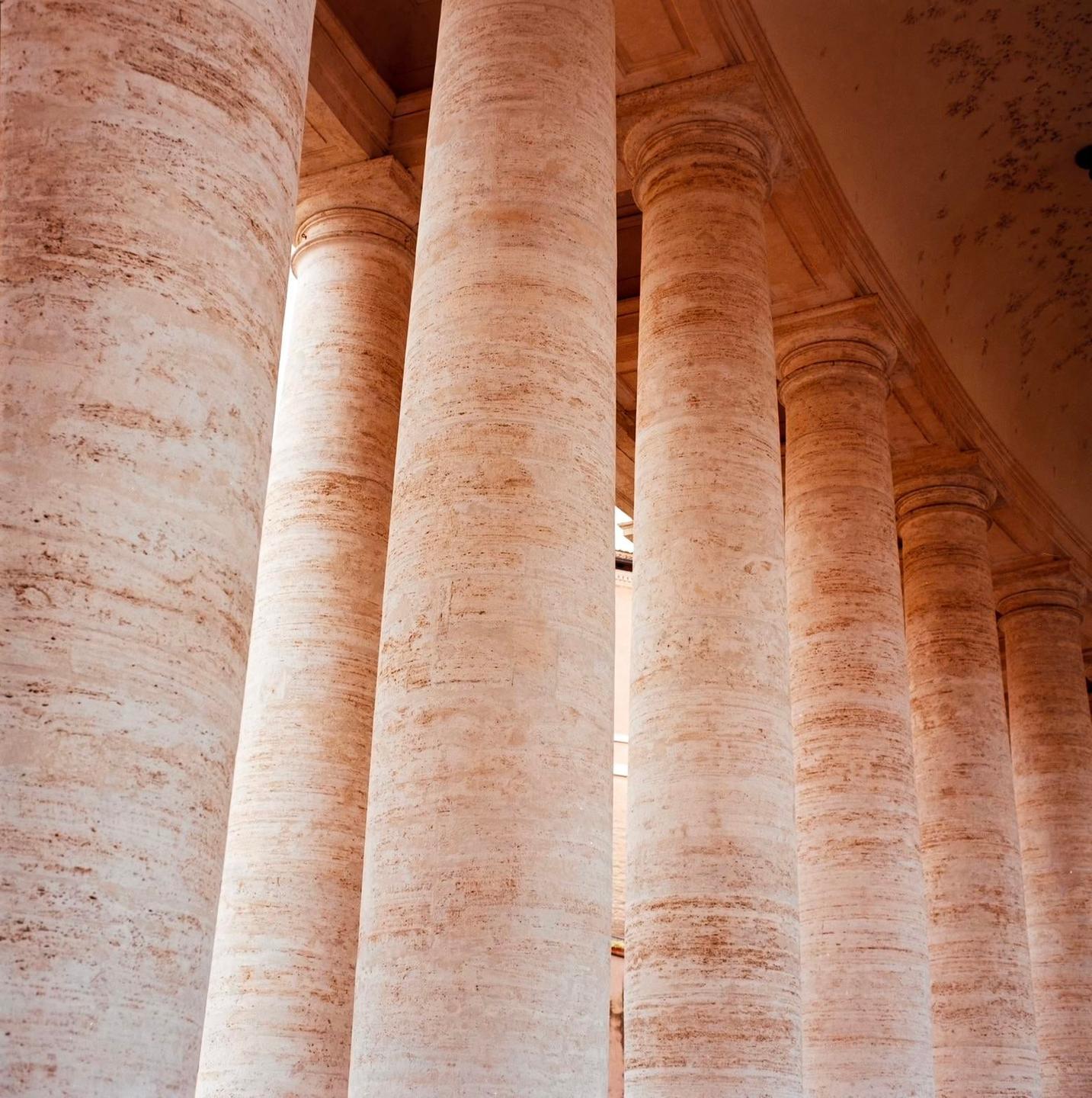 A row of large, textured stone columns stands in a building.