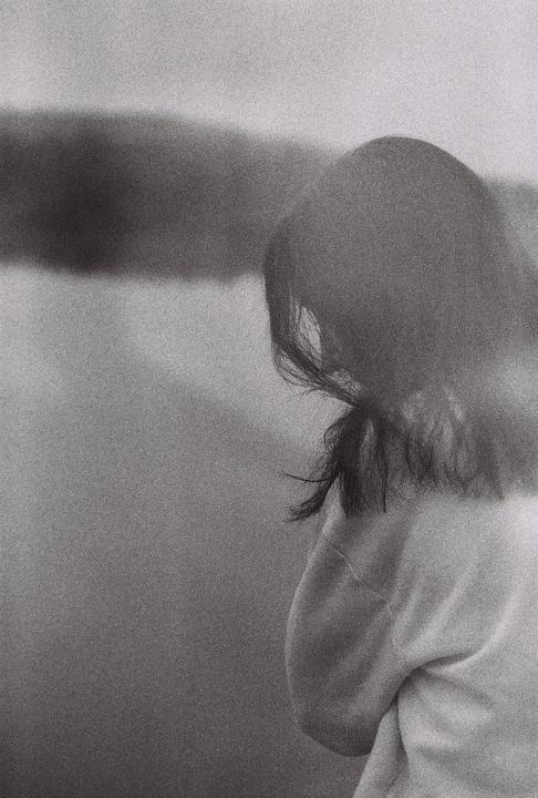 A woman with dark hair is seen from behind, looking away from the camera.