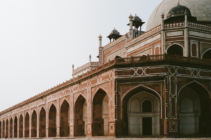 A large, ornate tomb with a dome and many arches is shown from a low angle.
