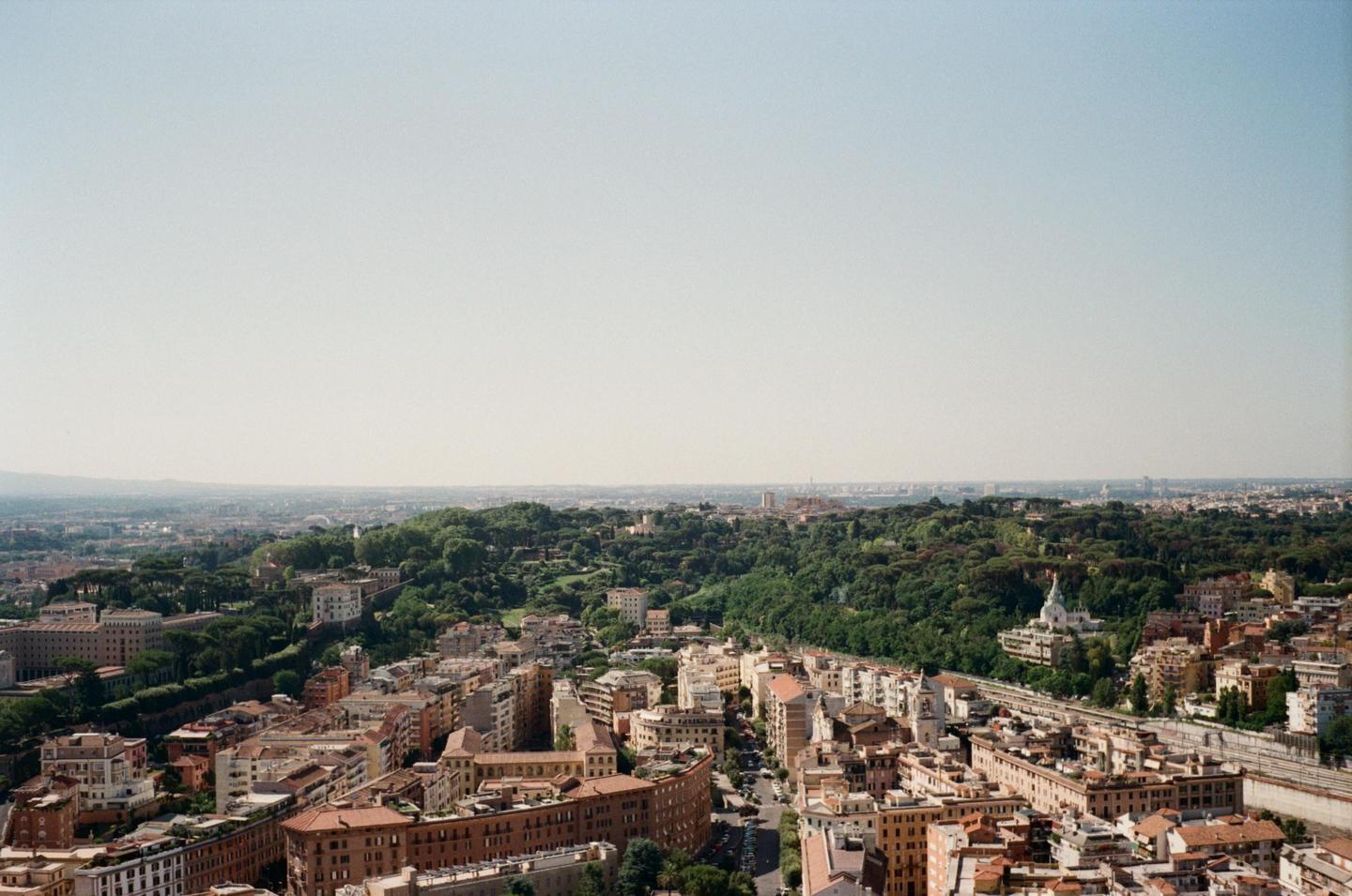 A panoramic view shows a city with many buildings and a large green area with trees.