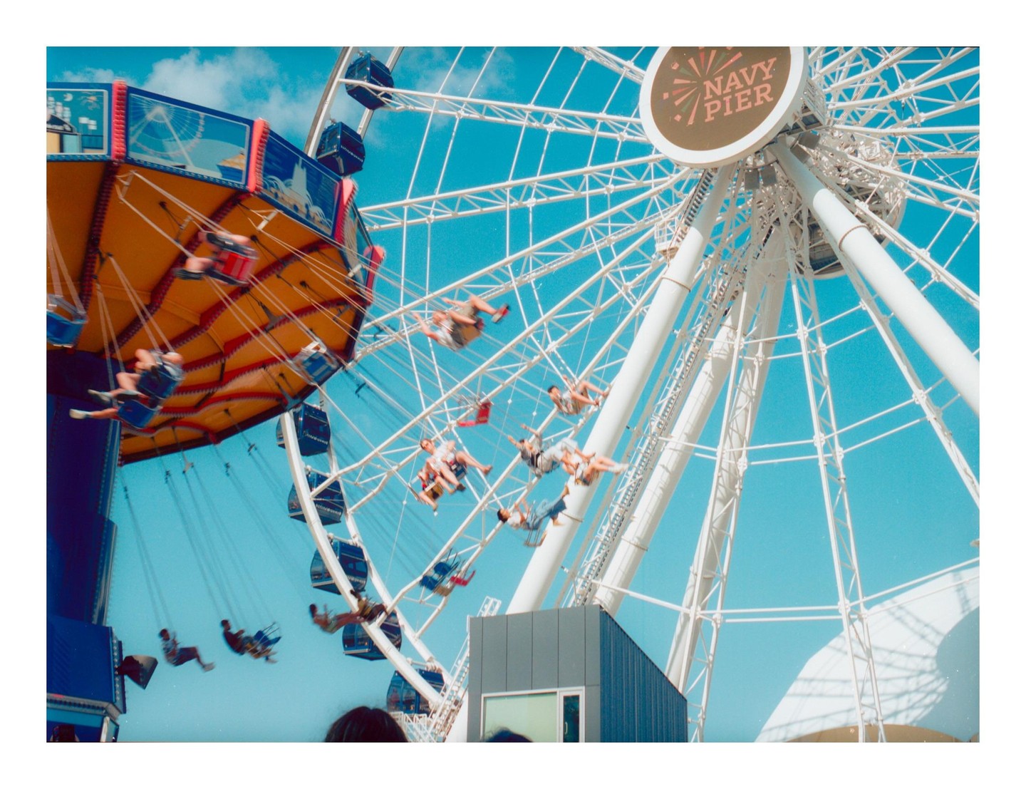 A Ferris wheel and a swing ride are visible against a bright blue sky.