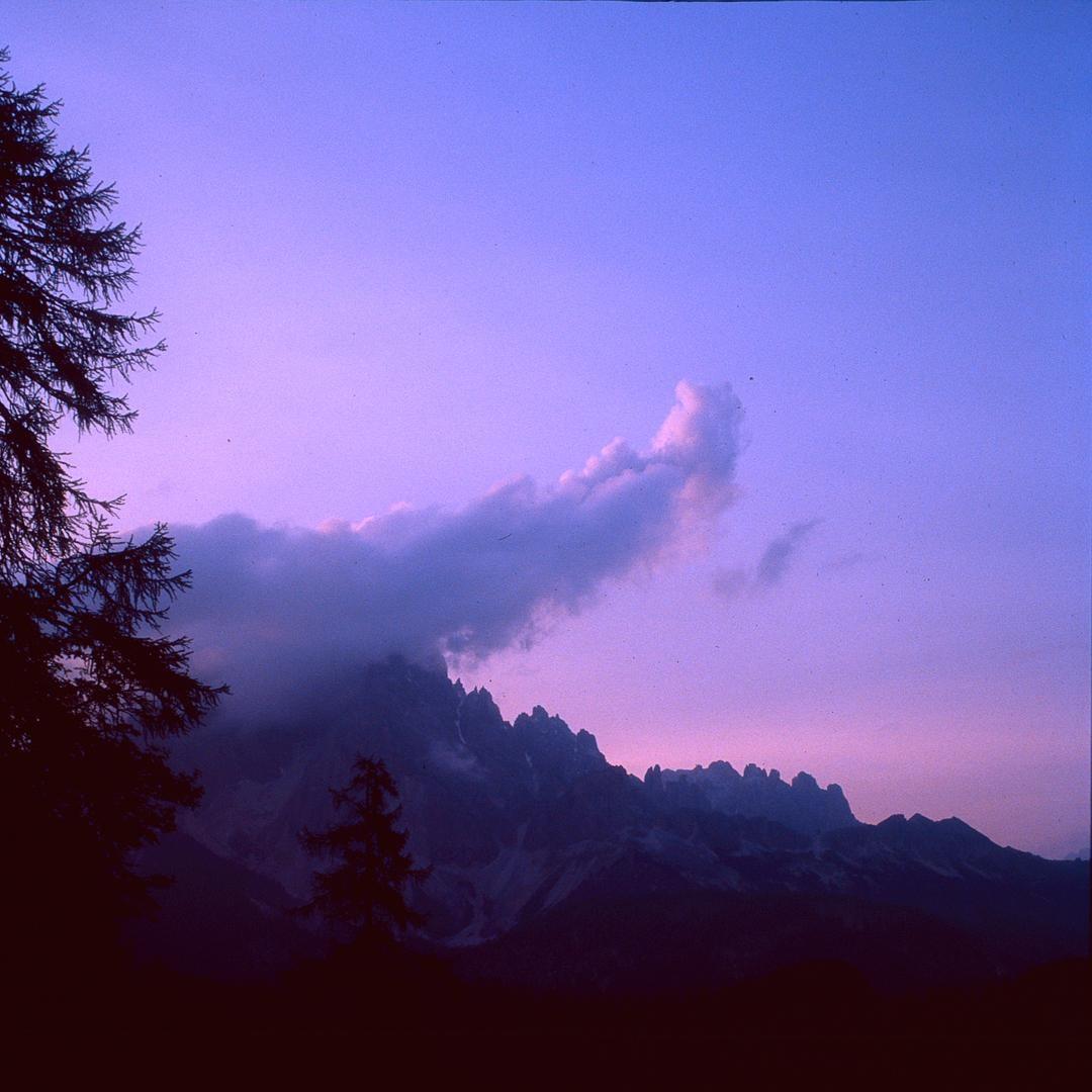 A mountain range is visible under a purple sky with clouds.