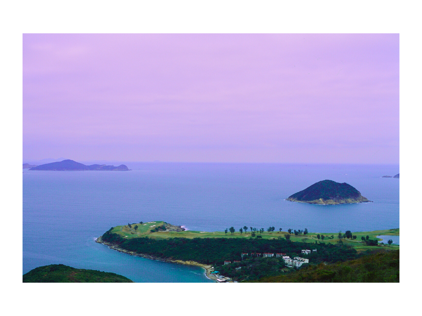 A golf course is visible on a peninsula surrounded by water and islands under a purple sky.